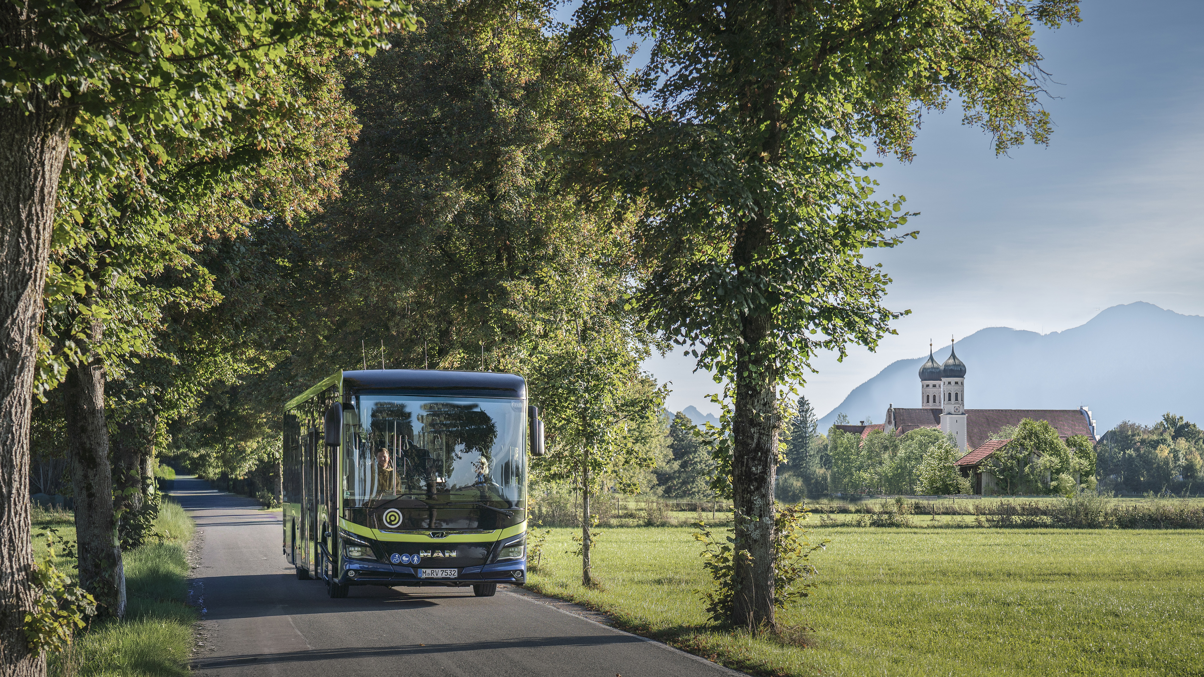 MVV-Regionalbus auf einer von Bäumen gesäumten Straße im Landkreis Bad Tölz-Wolfratshausen