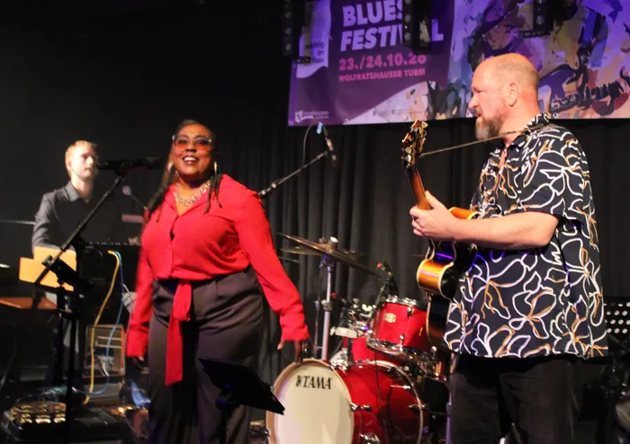 Sängerin Donnielle Graves in roter Bluse mit zwei Musikern des Vollmer Organ Trios auf der Bühne im Wolfratshauser Turm.
