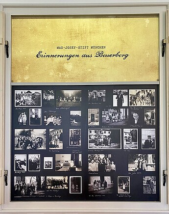 Dr. Christoph Kürzeder spricht bei der Eröffnung der Ausstellung „Seelentrost“ im Kloster Beuerberg in ein Mikrofon. Eine Ausstellungstafel zeigt historische Fotografien aus der Zeit des Max-Josef-Stifts im Kloster Beuerberg.