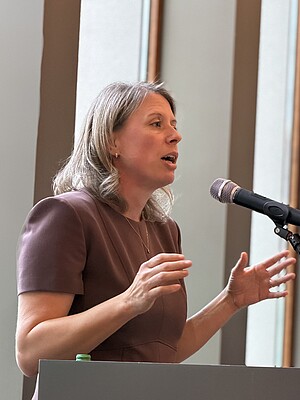 Jessica Keilholz-Busch – Franz Marc Museum Jessica Keilholz-Busch spricht am Rednerpult des Franz Marc Museums und gestikuliert mit beiden Händen vor einem Mikrofon.