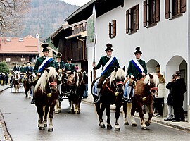 Reiter in grünen Trachten mit Federhüten auf geschmückten Pferden bei der Leonhardifahrt in Benediktbeuern.