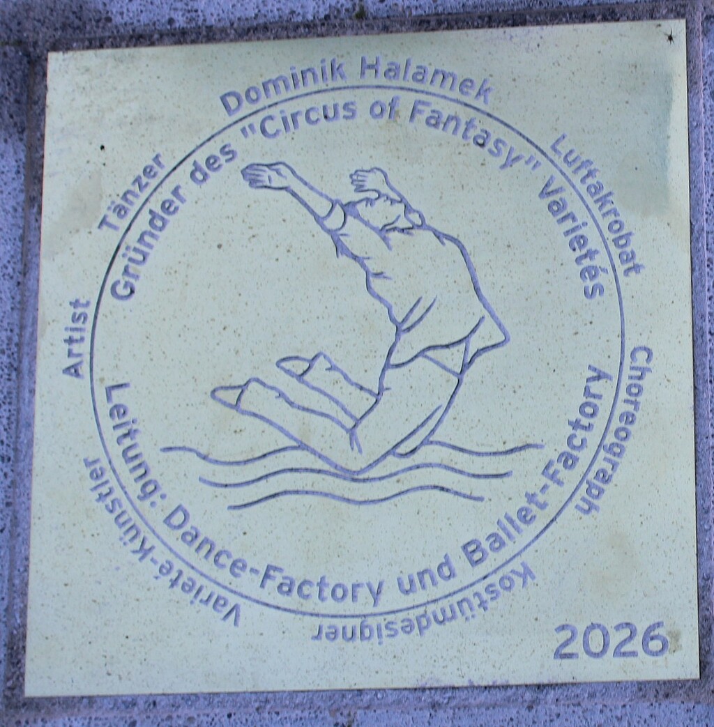 Messingtafel für Dominik Halamek auf dem Wolfratshauser „Walk of Fame“ Messingtafel für Dominik Halamek auf dem „Walk of Fame“ in Wolfratshausen mit einem Luftakrobaten über der Loisach