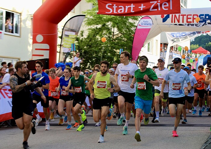 Läufer starten beim Alpenland Firmenlauf 2026 in Geretsried unter dem Startbogen