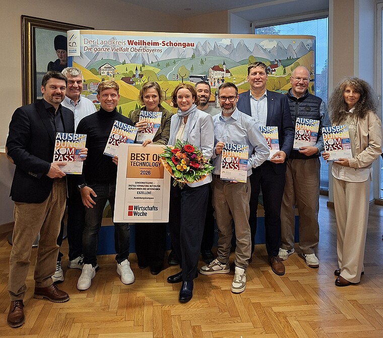Ausbildungskompass Weilheim-Schongau – Best of Technology Award 2026 Gruppenfoto zur Auszeichnung des Ausbildungskompasses Weilheim-Schongau mit dem Best of Technology Award 2026. Die Beteiligten halten Ausbildungskompasse, in der Mitte stehen Monika Uhl mit Blumenstrauß und die Auszeichnung.