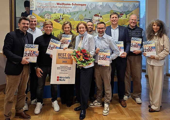 Gruppenfoto zur Auszeichnung des Ausbildungskompasses Weilheim-Schongau mit dem Best of Technology Award 2026. Die Beteiligten halten Ausbildungskompasse, in der Mitte stehen Monika Uhl mit Blumenstrauß und die Auszeichnung.