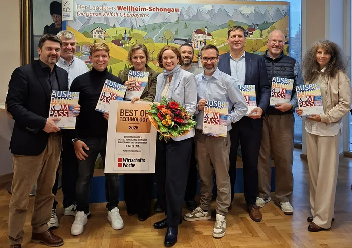 Gruppenfoto zur Auszeichnung des Ausbildungskompasses Weilheim-Schongau mit dem Best of Technology Award 2026. Die Beteiligten halten Ausbildungskompasse, in der Mitte stehen Monika Uhl mit Blumenstrauß und die Auszeichnung.